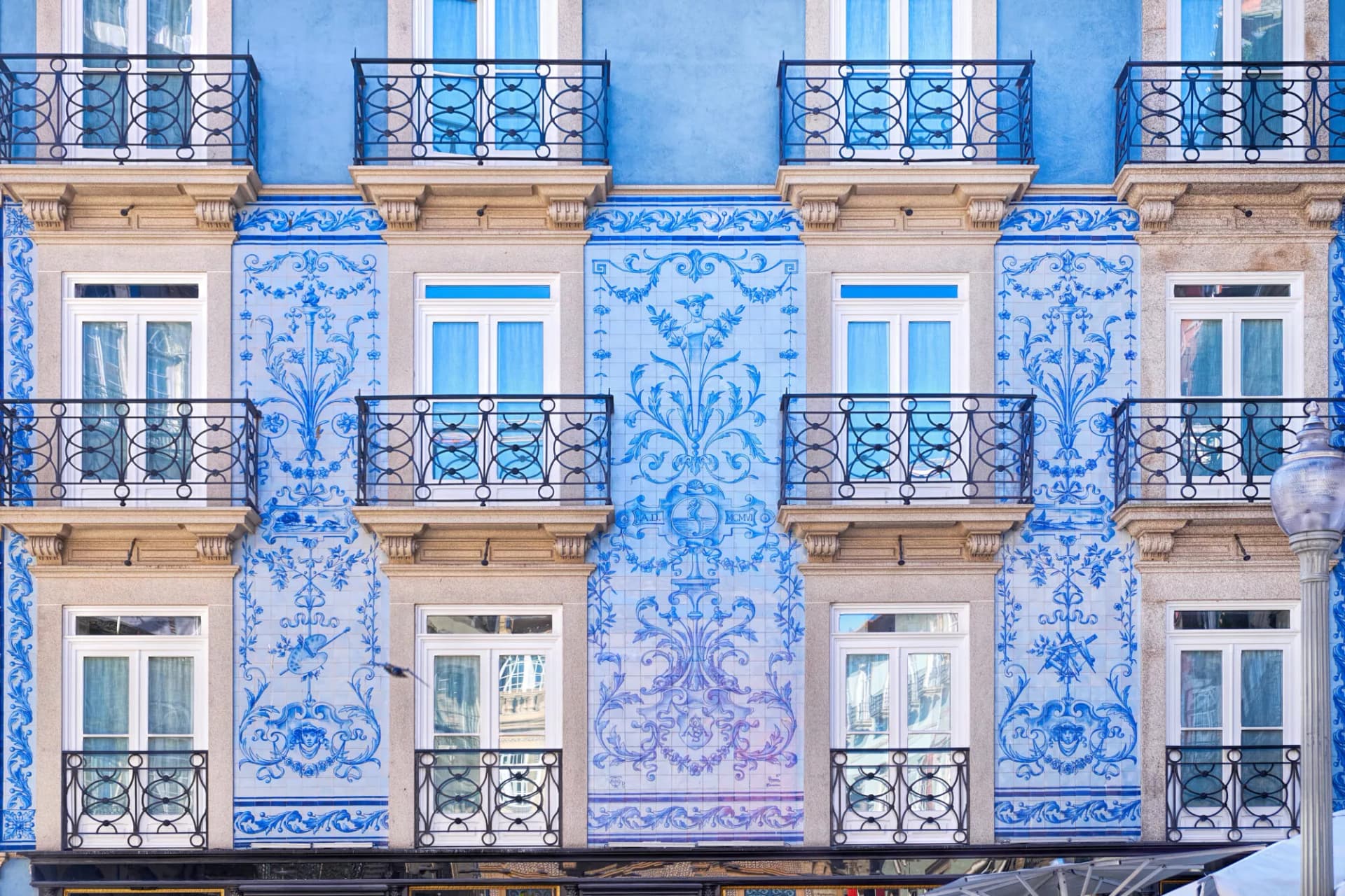 Building facade with blue and white azulejo tiles, balconies, and windows in Porto.