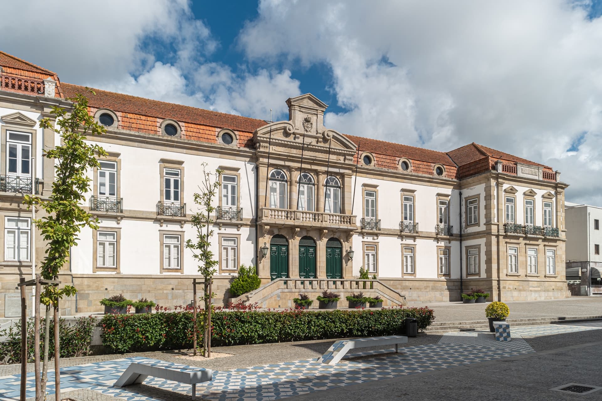 Historic white building with green doors and terracotta roof in Ovar square.