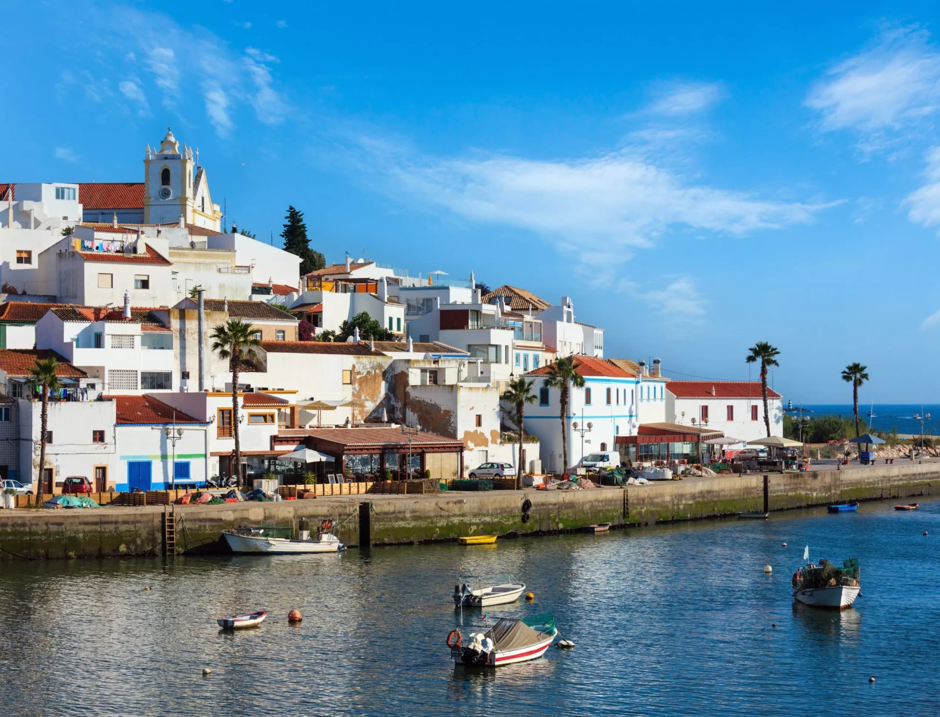 Ferragudo fishing village evening summer view with boats on water (near Marina Portimao, Lagoa, Algarve, Portugal). Peoples are unrecognizable.